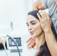 Frau erhält eine chiropraktische Behandlung, während ihr Kopf sanft gehalten wird