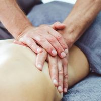 Nahaufnahme einer Massage, bei der Hände den Rücken einer Person massieren