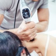 Stoßwellentherapie-Behandlung am Nacken einer Patientin